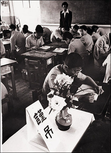 광주민중항쟁 시위에서 희생된 한 학생의 빈 책상 위에 급우들이 꽃을 꽂아 조의를 표한 가운데 학생들이 친구 잃은 슬픔을 안고 수업하고 있다.(6.1)